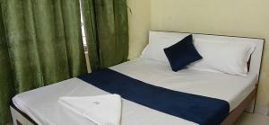 a bed with a blue and white pillow and a window at Hotel O Sharan Guest House in Calcutta Bara Bazar
