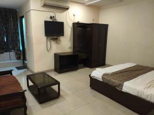 a bedroom with a bed and a desk and a tv at Hotel O Laxmi Narsimha Temple Banjara Hills in Hyderabad