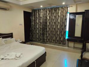a bedroom with a bed and a window with curtains at Hotel O Laxmi Narsimha Temple Banjara Hills in Hyderabad +8 photos