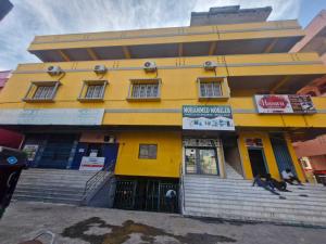a yellow building with a sign on it at - Hotel O Machilipatnam Railway Station Formerly Hasini Celebrations in Machilīpatnam +8 photos
