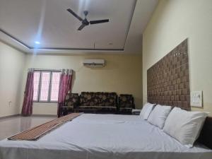 a bedroom with a large bed with a ceiling fan at - Hotel O Machilipatnam Railway Station Formerly Hasini Celebrations in Machilīpatnam