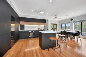 eine Küche mit schwarzen Schränken und eine Bar mit Hockern in der Unterkunft Among The Vines in North Rothbury