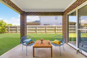 un patio con 2 sillas, una mesa y una mesa en Five Bedrooms Near Schofields Station Direct Access to Sydney University & Parramatta, en Schofields