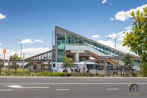 un gran edificio de cristal con una escalera frente a una calle en Five Bedrooms Near Schofields Station Direct Access to Sydney University & Parramatta, en Schofields
