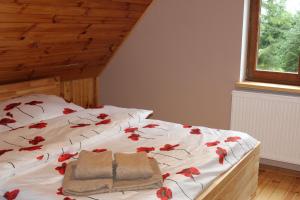 a bedroom with a bed with red flowers on it at Mazurska Chata Czepiela in Langendorf +29 photos