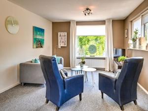 a living room with blue chairs and a table at Stunning apartment in Schoorl, North Hollandâ you can bike to the beach in Schoorl