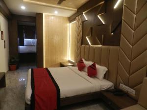 a bedroom with a large bed with red pillows at Hotel The Novelty in Kānpur