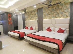 two beds with red pillows in a bedroom at Hotel The Novelty in Kānpur