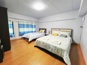Un dormitorio con dos camas y suelo de madera. en BirdHostel Chiangrai, en Chiang Rai