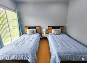 Dos camas individuales en una habitación con ventana. en BirdHostel Chiangrai, en Chiang Rai