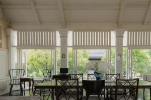 a dining room with tables and chairs and windows at Makka Hotel in Chiang Mai
