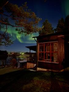a cabin with a window and the aurora in the sky at The paradise by the beach in Långviken +53 photos