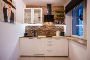 een keuken met witte kasten en een bakstenen muur bij Clara in Rzeszów