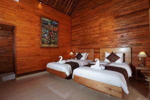 3 Betten in einem Zimmer mit Holzwänden in der Unterkunft Puri Bucuana Villa in Bedahulu