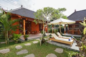 ein Haus mit einer Terrasse mit einem Sofa und einem Sonnenschirm in der Unterkunft Puri Bucuana Villa in Bedahulu
