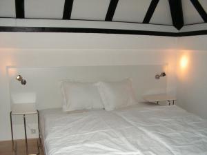 een bed met witte lakens en kussens in een kamer bij Frankenau 36 in Frankenau