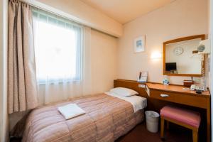a hotel room with a bed and a desk and a mirror at 南部ホテル in Kitakami