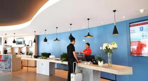 twee mannen aan een balie in een kantoor bij Ibis Ya An Langqiao in Shaping