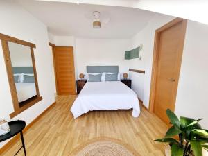 a bedroom with a white bed and a mirror at Vila, 132 - II in San Cosme de Barreiros