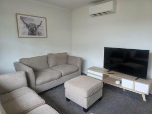 a living room with a couch and a flat screen tv at Modern, House in central Palmerston North in Palmerston North