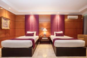 two beds in a hotel room with purple walls at Hotel Bumi Senyiur in Samarinda