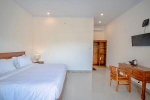 a bedroom with a bed and a desk and a television at Moringa Pandawa Guest House in Ungasan +7 photos