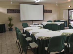 a conference room with tables and chairs and a screen at Insel Fehmarn Hotel in Apia