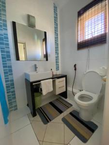 a bathroom with a toilet and a sink and a mirror at Grand Bay 4Bed Triplex Villa with Community Pool in Grand Baie
