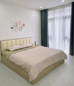 ein Schlafzimmer mit einem großen Bett vor einem Fenster in der Unterkunft Creamy home - Homestay Vinhomes Ocean Park 3 in Ðình Loan