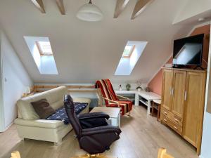 een woonkamer met een bank, een tv en dakramen bij Goldener Anker, verschiedene gemütliche Ferienwohnungen in Rheinsberg