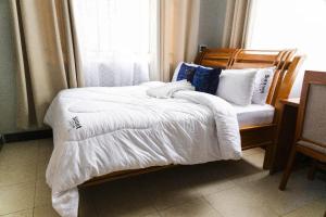 a bedroom with a bed with white blankets and pillows at Sunset Lodge Salasala in Dar es Salaam