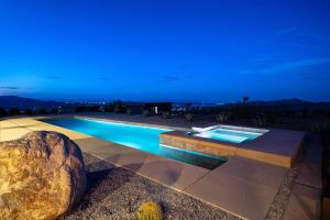 a swimming pool at night with a large rock next to it at The Coza by Fieldtrip - Modern Retreat w Pool Spa in Joshua Tree