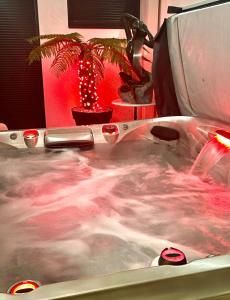 a bath tub filled with water with a palm tree at cocoon romantique avec jacuzzi proche plage in Saint-Gildas-de-Rhuys