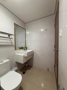 a white bathroom with a sink and a toilet at The Banyan Rest in Balibaguhan