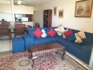 a living room with a blue couch with colorful pillows at Cicada 8 in Ramsgate
