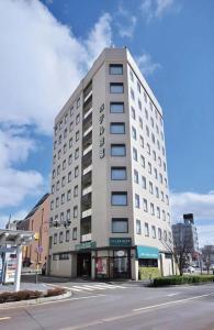 ein hohes weißes Gebäude auf einer Straße mit einer Straße in der Unterkunft Hotel Keifuku Fukui Ekimae in Fukui