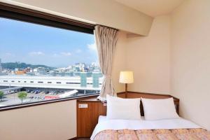 ein Schlafzimmer mit einem Fenster mit Blick auf die Stadt in der Unterkunft Hotel Keifuku Fukui Ekimae in Fukui