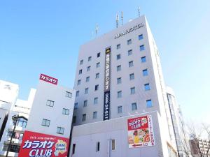 a white building with a sign on the side of it at APA Hotel Owari Ichinomiya Eki-mae in Ichinomiya