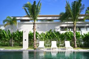 a pool with chairs and palm trees in front of a building at Asherah Villa By Asherah Team in Ban Phru Champa