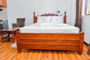 a bedroom with a bed with white sheets and a desk at Monalisa Studio Apartments in Gatunga