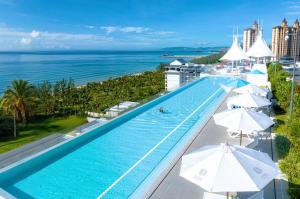 an overhead view of a swimming pool with umbrellas and the ocean at Vaperse Hainan Clear Water Bay in Lingshui