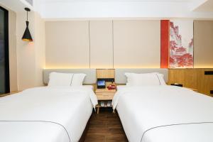 two beds in a room with white walls at Chenlong Cafe Hotel in Guangzhou