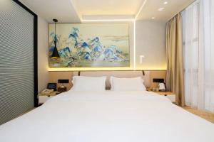a bedroom with a white bed and a painting on the wall at Chenlong Cafe Hotel in Guangzhou