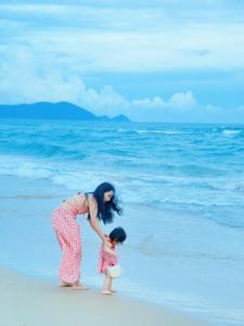 a woman playing with a small child on the beach at Vaperse Hainan Clear Water Bay in Lingshui