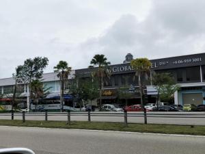 Kampong JeramにあるM GLOBAL HOTELの通りの前にヤシの木がある建物