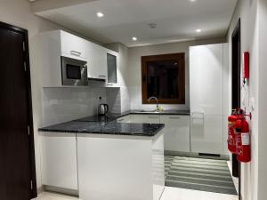 a kitchen with white cabinets and a black counter top at Beiruty House -Elegant Family Seaside Villa in As Sīfah