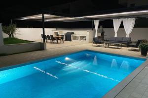 a large blue swimming pool in a backyard at night at Villa Suzy in Medulin