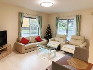 a living room with two couches and a christmas tree at Solf潮崎 in Itoman