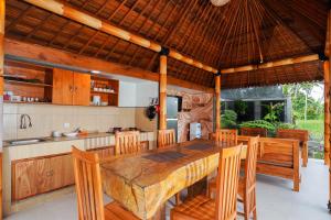 eine Küche und ein Esszimmer mit einem Holztisch und Stühlen in der Unterkunft Puri Bucuana Villa in Bedahulu