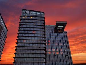 a tall building with a sunset in the background at Hotel Indigo Zhuhai Xiangzhou by IHG in Zhuhai